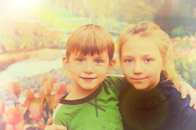 Sister with brother on the background of tulips, the concept of March 8 and Valentine`s Day