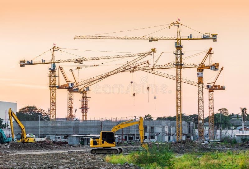 Building construction site with tower crane and backhoe machinery in sunset vintage tone color. Building construction site with tower crane and backhoe machinery in sunset vintage tone color