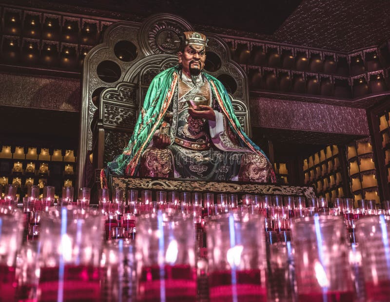 Sitting asian god with red candles in front of him stock photo
