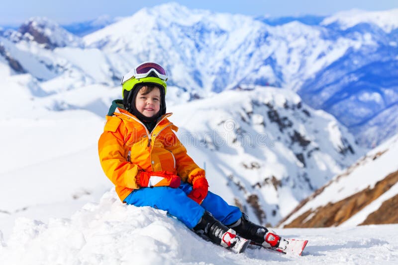 Sitting boy wearing ski mask and helmet in winter