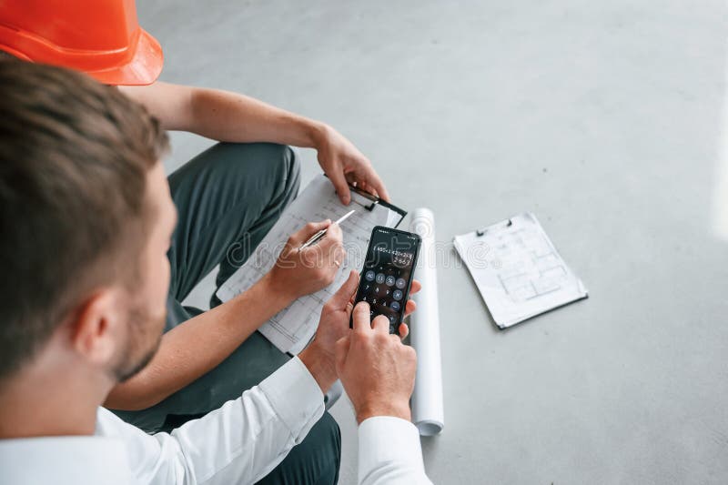 Sitting, Using Calculator. Manager with Foreman are Working on the