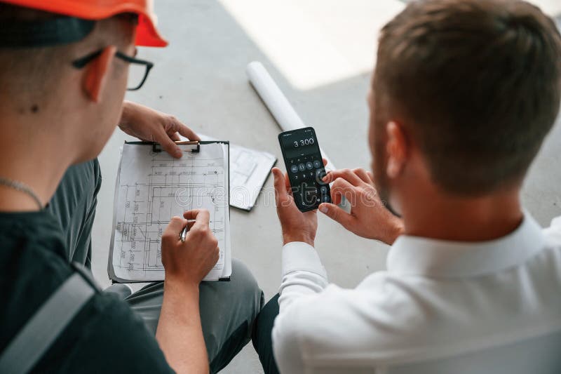 Sitting, Using Calculator. Manager with Foreman are Working on the