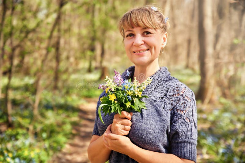 Situación atractiva hermosa de la mujer en el bosque y disfrutar de la naturaleza Mujer adulta preciosa con un ramo de flores imagen de archivo libre de regalías Situación atractiva hermosa de la mujer en el bosque y disfrutar de la naturaleza Mujer adulta preciosa con un ramo de flores imagen de archivo libre de regalías