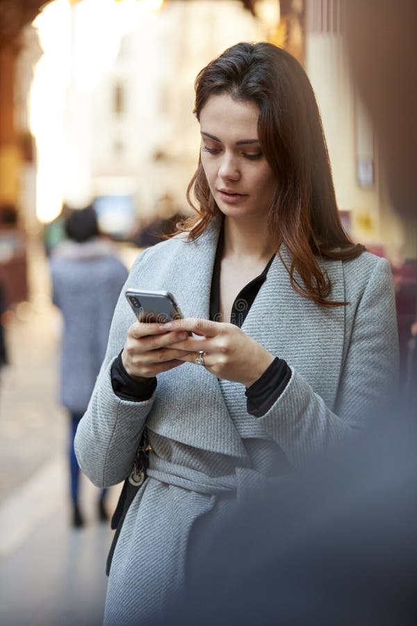 Situación blanca joven de la empresaria en una calle ocupada de Londres usando el smartphone, cierre para arriba, vertical imagenes de archivo Situación blanca joven de la empresaria en una calle ocupada de Londres usando el smartphone, cierre para arriba, vertical imagenes de archivo