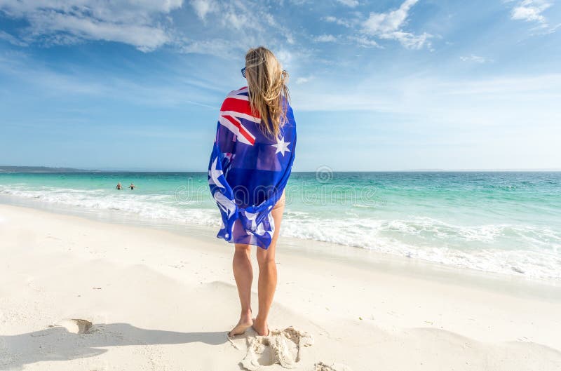 Situación de la mujer en la playa con la bandera envuelta alrededor de ella fotos de archivo libres de regalías Situación de la mujer en la playa con la bandera envuelta alrededor de ella fotos de archivo libres de regalías
