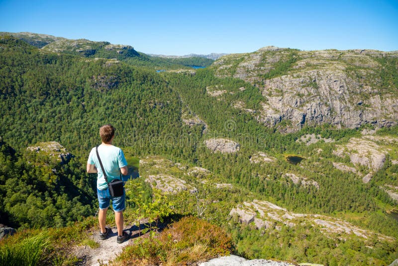 Situación del caminante en Preikestolen y mirada en la montaña al lado de Preikestolen en Noruega imágenes de archivo libres de regalías Situación del caminante en Preikestolen y mirada en la montaña al lado de Preikestolen en Noruega imágenes de archivo libres de regalías