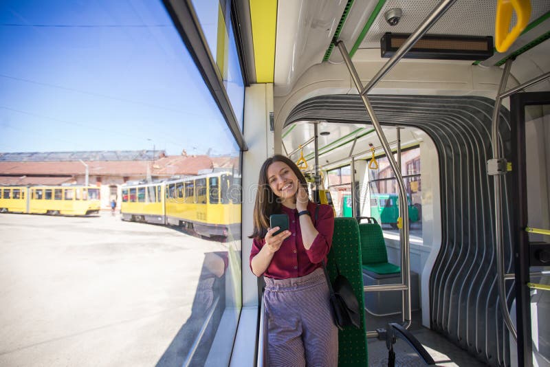 Situación del pasajero de la mujer joven con smartphone mientras que se mueve en la tranvía moderna fotografía de archivo Situación del pasajero de la mujer joven con smartphone mientras que se mueve en la tranvía moderna fotografía de archivo