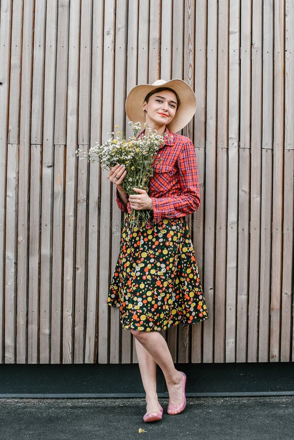 Situación elegante de la muchacha con las flores Mujer hermosa cerca de una pared de madera Estilo de la primavera Paseo del vera imagenes de archivo Situación elegante de la muchacha con las flores Mujer hermosa cerca de una pared de madera Estilo de la primavera Paseo del vera imagenes de archivo