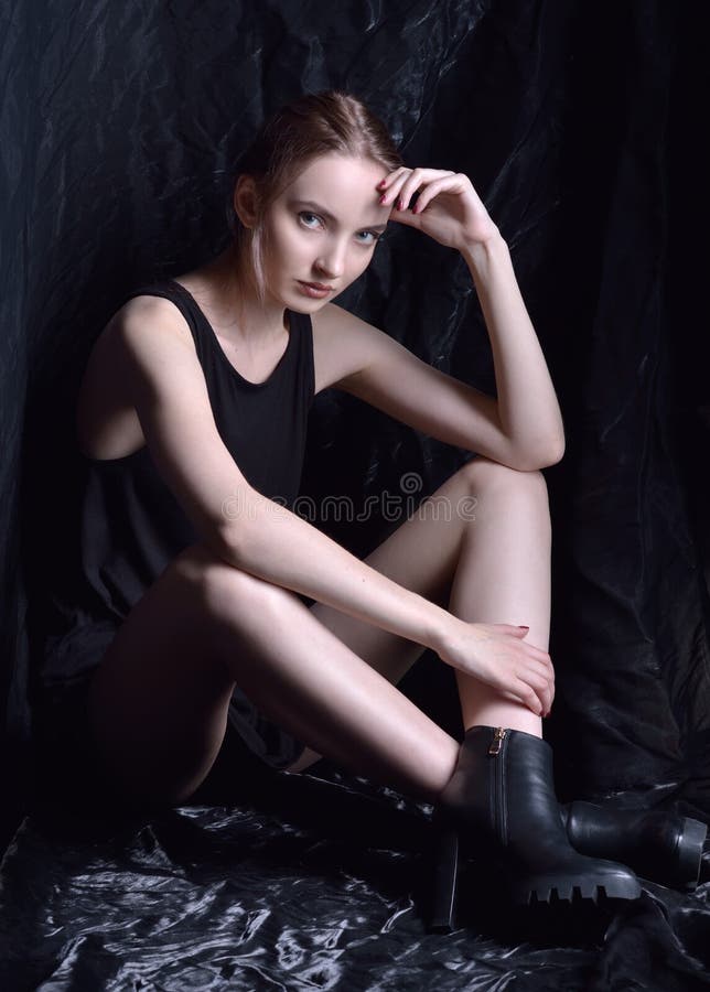 Sitzende Schönheit in der schwarzen Spitze und Schuhe im dunklen Studio lizenzfreie stockbilder Sitzende Schönheit in der schwarzen Spitze und Schuhe im dunklen Studio lizenzfreie stockbilder