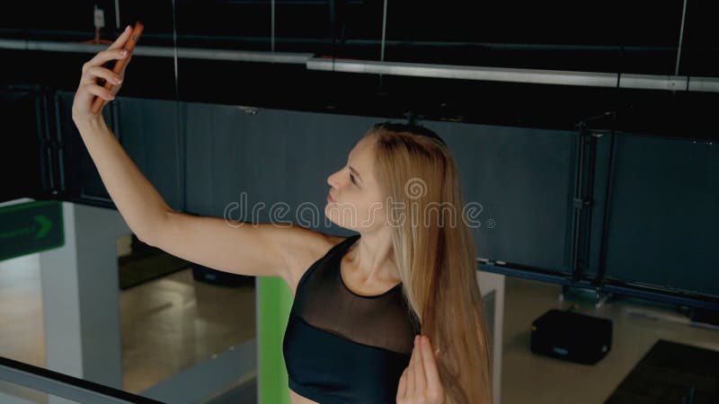 Sitzfrauenstellung in der Turnhalle und selfie mit Smartphone. Konzepttechnologie