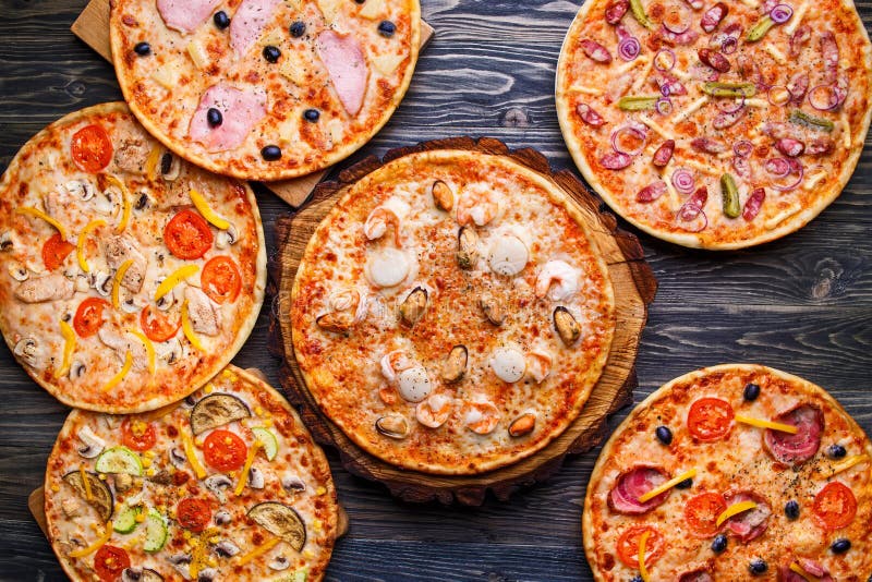 Six different pizza set for menu on the wooden table. Italian food traditional cuisine. Pizzas with salami, seafood, ham, bacon and olives, chicken and mushrooms and vegetarian, top view