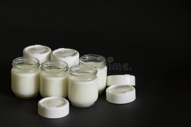 Six jars with milk on a black background