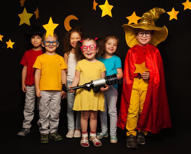 Group of six boys and girls in stargazers costumes watching handmade stars and moon against black background. Group of six boys and girls in stargazers costumes watching handmade stars and moon against black background