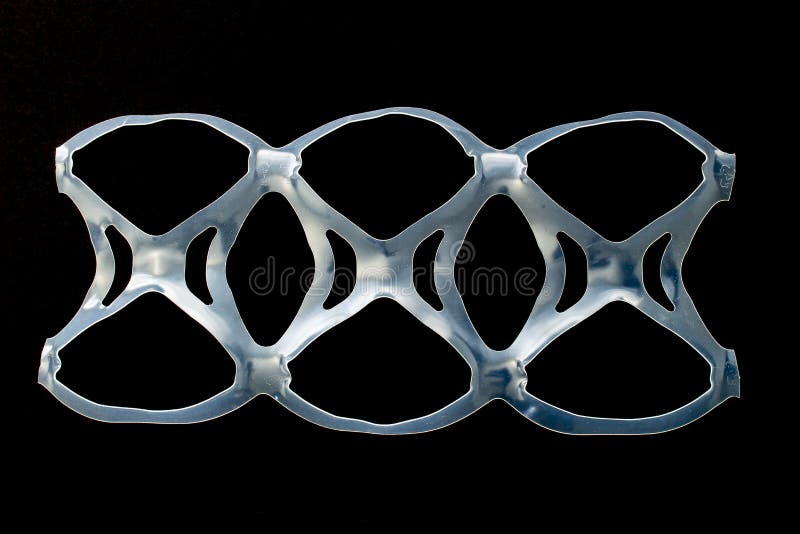 Isolated six pack rings or six pack yokes, connected plastic rings used in multi-packs of beverage on a black background. Isolated six pack rings or six pack yokes, connected plastic rings used in multi-packs of beverage on a black background