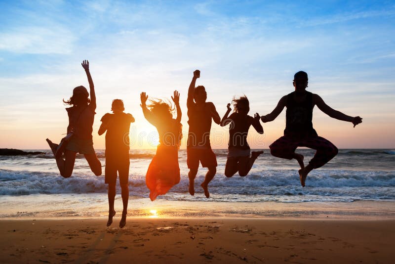 Six people jumping on beach at sunset.