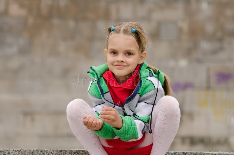 Six year old girl crouched on the background of a granite wall royalty free stock photography Six year old girl crouched on the background of a granite wall royalty free stock photography