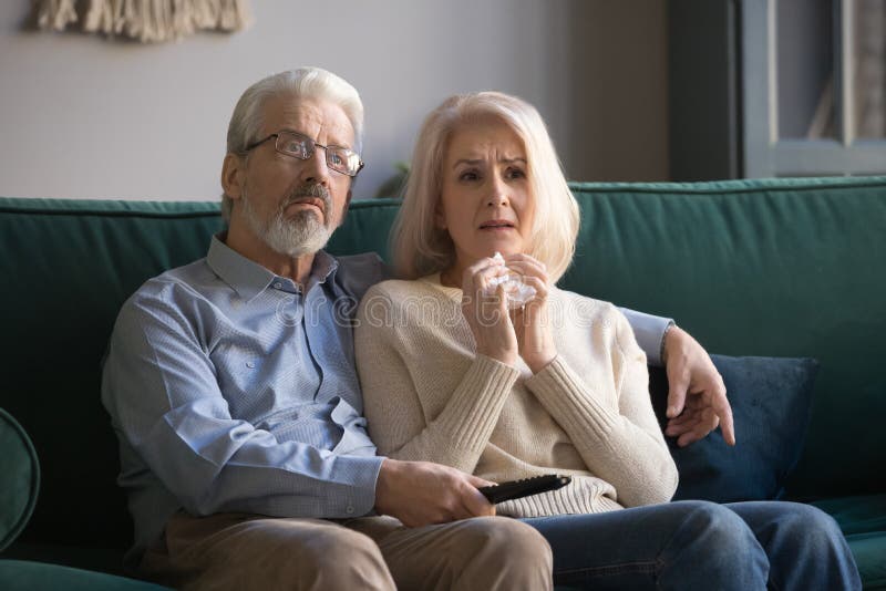 Sorrowful elderly couple spend free time watching melodrama movie royalty free stock photos