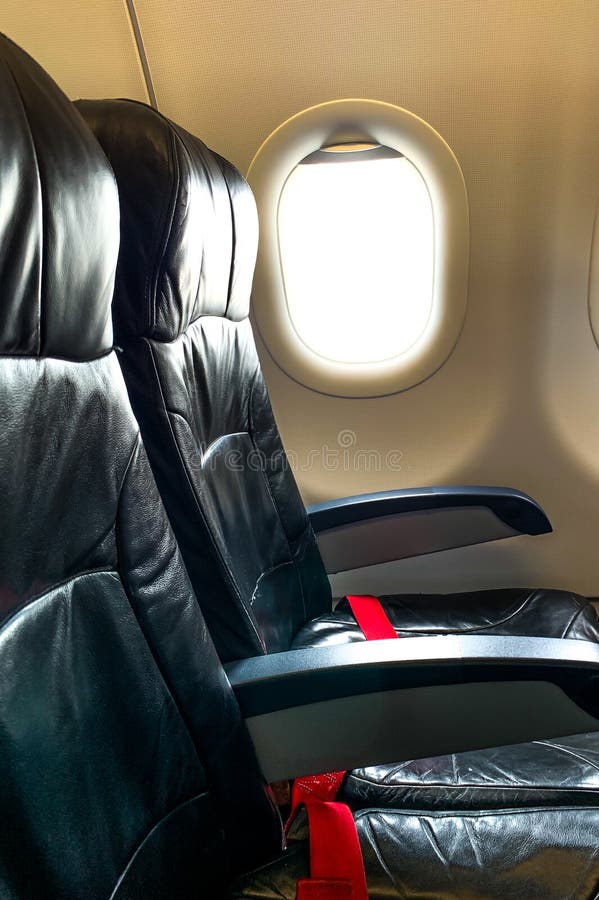 Siège noir d'avion ceinture de sécurité et fenêtre rouges dans la classe touriste de cabine image libre de droits Siège noir d'avion ceinture de sécurité et fenêtre rouges dans la classe touriste de cabine image libre de droits