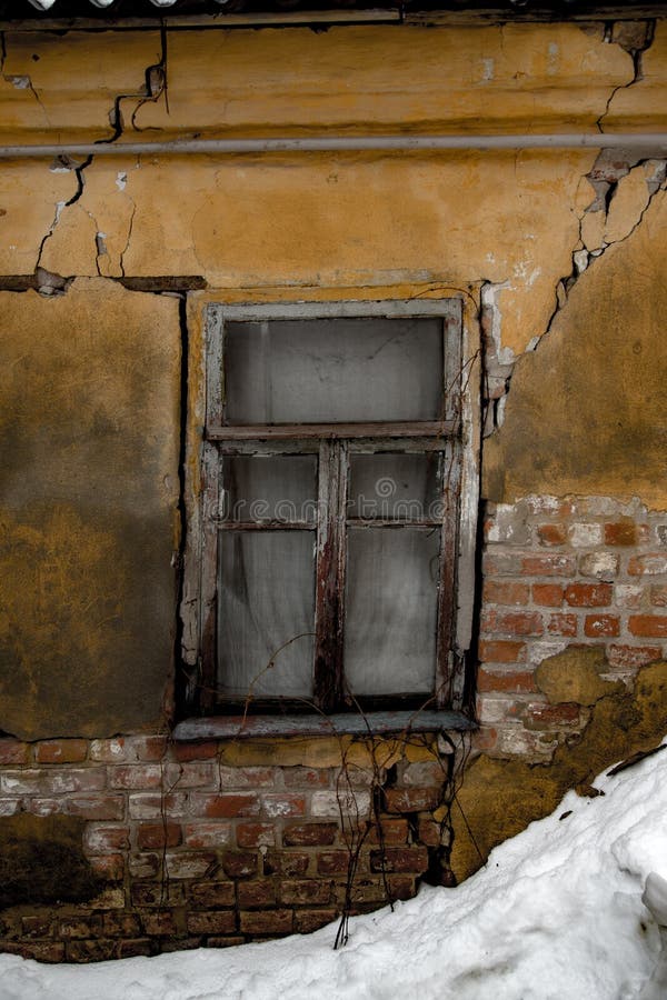Sjaskig grungy sprucken vägg, brutna fönster, övergett hus, vinter, armodbegrepp royaltyfri bild