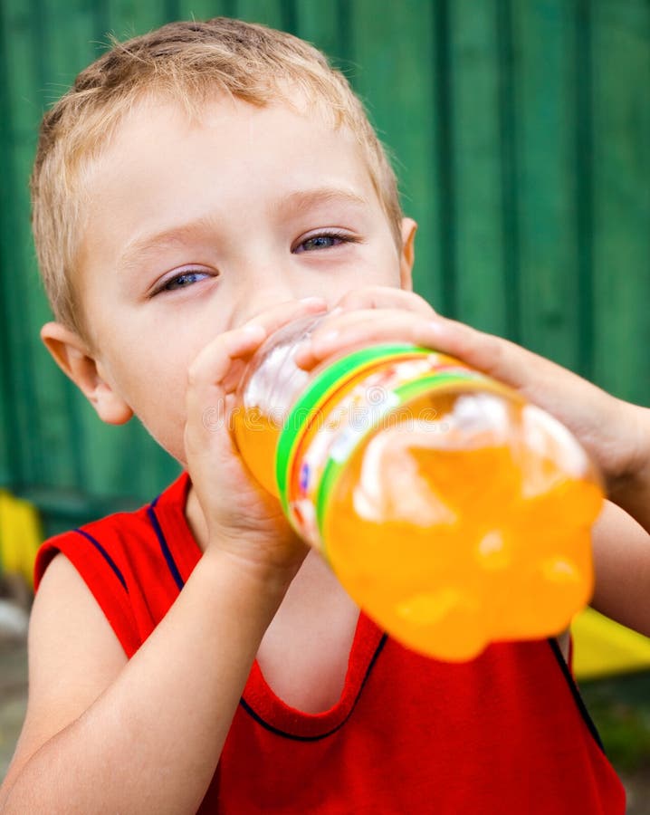Thirsty child drinking unhealthy bottled orange soda. Thirsty child drinking unhealthy bottled orange soda