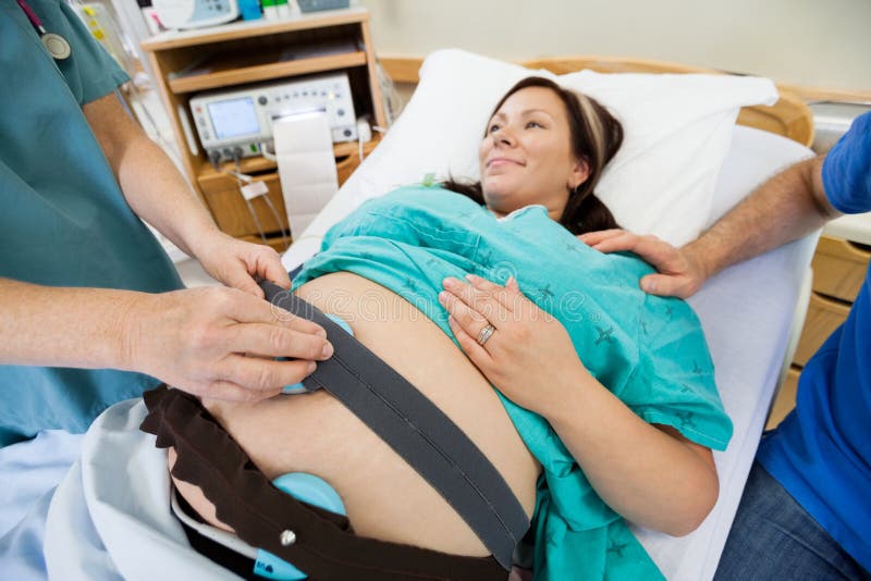 Sjuksköterska Preparing Pregnant Woman för hjärtslag royaltyfri fotografi Sjuksköterska Preparing Pregnant Woman för hjärtslag royaltyfri fotografi