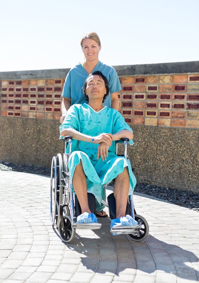 Sjuksköterska Pushing Relaxed Patient på rullstolen på royaltyfria bilder Sjuksköterska Pushing Relaxed Patient på rullstolen på royaltyfria bilder