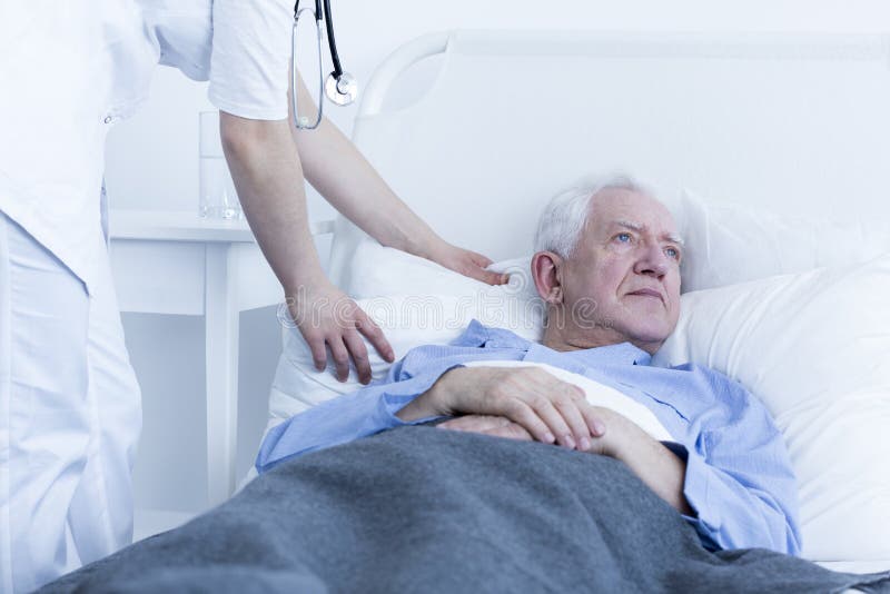 Sjuksköterska som fluffar kudden av patienten royaltyfria bilder Sjuksköterska som fluffar kudden av patienten royaltyfria bilder