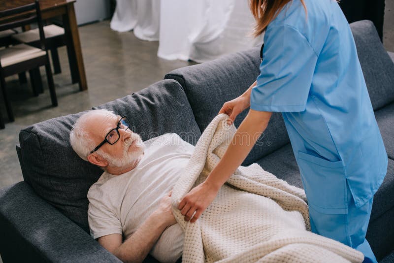 Sjuksköterska som hjälper den gamla patienten att täcka arkivbilder Sjuksköterska som hjälper den gamla patienten att täcka arkivbilder