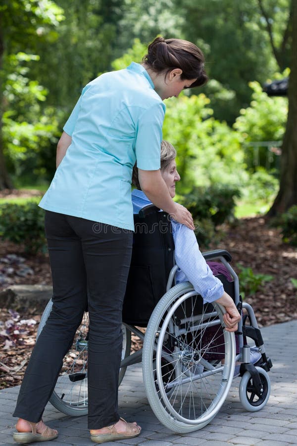 The nurse went out for a walk with an older women in a wheelchair. The nurse went out for a walk with an older women in a wheelchair