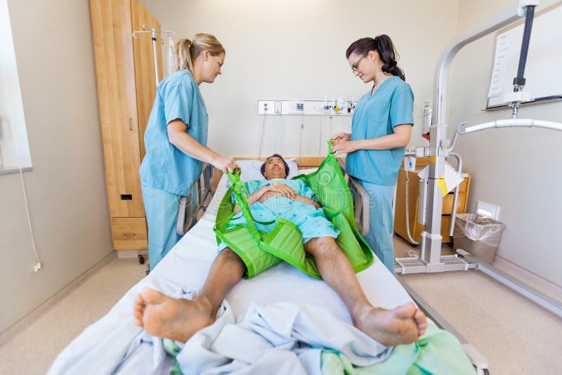 Sjuksköterskor som förbereder den manliga patienten, innan överföring royaltyfria bilder Sjuksköterskor som förbereder den manliga patienten, innan överföring royaltyfria bilder