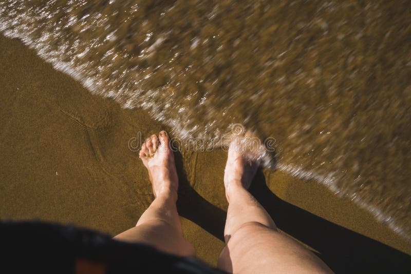 Självfoto av fötterna på stranden, vågor som kommer mot fötterna royaltyfri bild Självfoto av fötterna på stranden, vågor som kommer mot fötterna royaltyfri bild