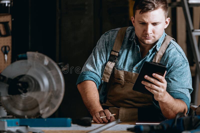 Self-employed machine constructor calculating costs while working at manufacturing plant. Self-employed machine constructor calculating costs while working at manufacturing plant