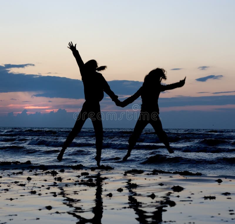 Girls silhouettes jumping near sea at sunset. Girls silhouettes jumping near sea at sunset..