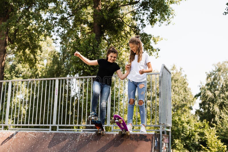 Skakare, barn flickor åker på penny board på sportramp vid solnedgången tillsammans. sportutrustning för barn arkivbilder