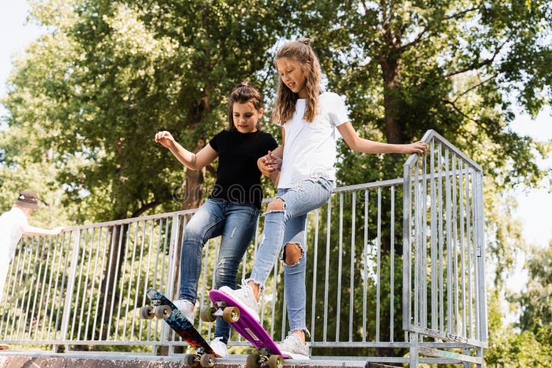 Skakare, barn flickor åker på penny board på sportramp vid solnedgången tillsammans. sportutrustning för barn royaltyfria bilder