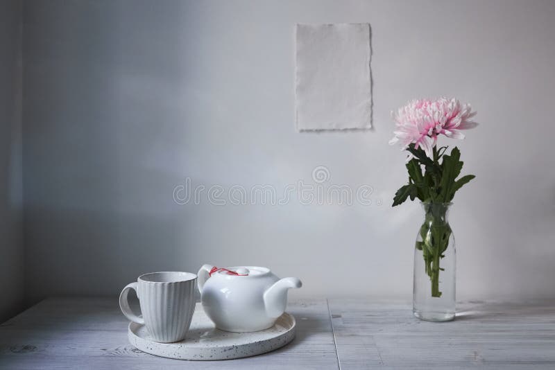 Scandinavian style. Interior Design. Large pink chrysanthemum in a long glass vase. Cup and tea pot on the tray. Empty space for text. Scandinavian style. Interior Design. Large pink chrysanthemum in a long glass vase. Cup and tea pot on the tray. Empty space for text