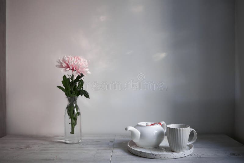 Scandinavian style. Interior Design. Large pink chrysanthemum in a long glass vase. Cup and tea pot on the tray. Empty space for text. Scandinavian style. Interior Design. Large pink chrysanthemum in a long glass vase. Cup and tea pot on the tray. Empty space for text