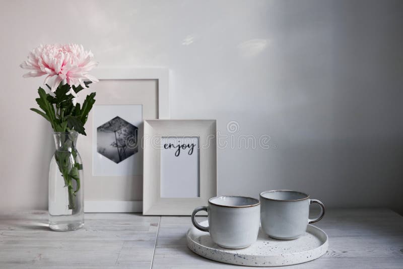 Scandinavian style. Interior Design. Large pink chrysanthemum in a long glass vase. Two cups of different size. Frame for photo. Empty space for text. Scandinavian style. Interior Design. Large pink chrysanthemum in a long glass vase. Two cups of different size. Frame for photo. Empty space for text