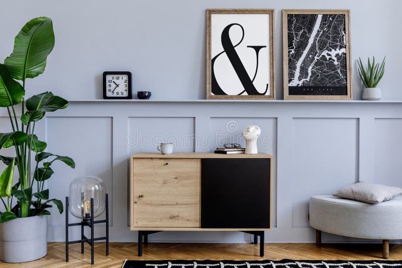 Skandinaviska insidan av vardagsrummet med två uppåtriktade affischramar, trävaruprodukter, designad svart lampa, växter, dekorat arkivfoton