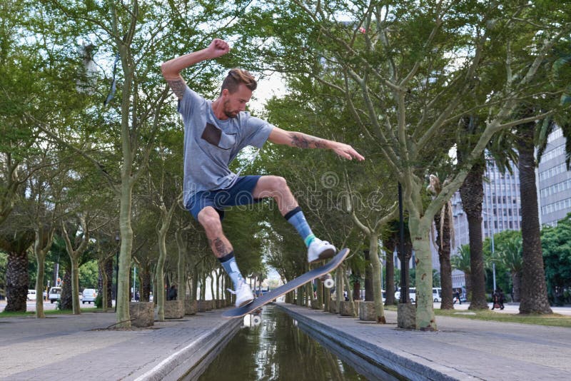 Skateboard saut et rivière avec l'homme en ville pour la culture sports extrêmes et le tour flip. Hobby de remise en forme et ligu images stock