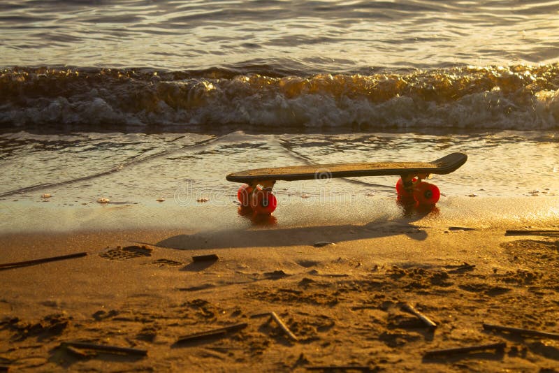 Skateboard στην άμμο στην παραλία στο ηλιοβασίλεμα στοκ εικόνα Skateboard στην άμμο στην παραλία στο ηλιοβασίλεμα στοκ εικόνα