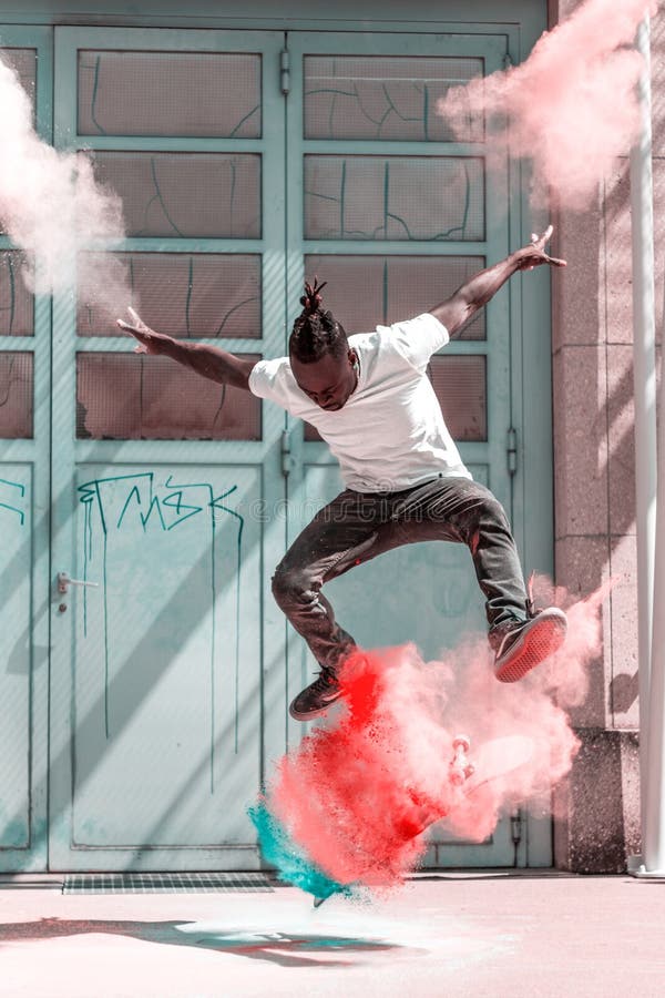 Skateboarder doing kickflip with colorful holi powder royalty free stock image Skateboarder doing kickflip with colorful holi powder royalty free stock image