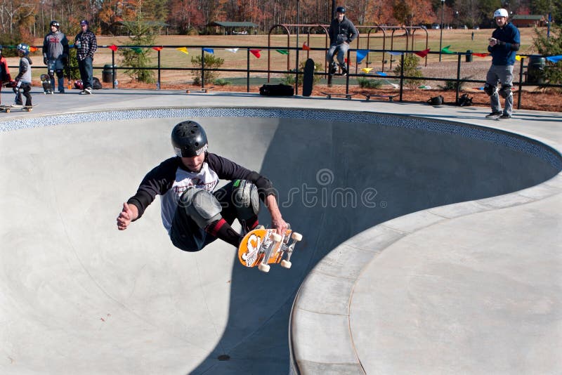 Skateboarder Grabs Board Doing Trick In Big Bowl