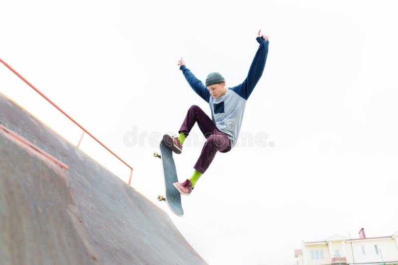 A skateboarder teenager in a hat does a trick with a jump on the ramp. A skateboarder is flying in the air