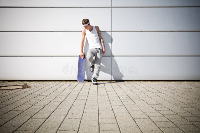 Bruslař drží svůj skateboard, zatímco pauzu.