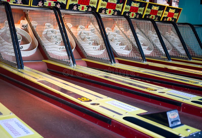 A row of midway Skeeball bowling amusement game at an arcade. When you get the ball into the target it pays out with tickets you can redeem for prizes. A row of midway Skeeball bowling amusement game at an arcade. When you get the ball into the target it pays out with tickets you can redeem for prizes.