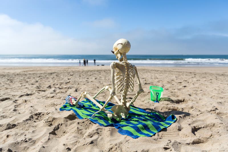skeleton-sits-beach-towel-relaxing-sand-