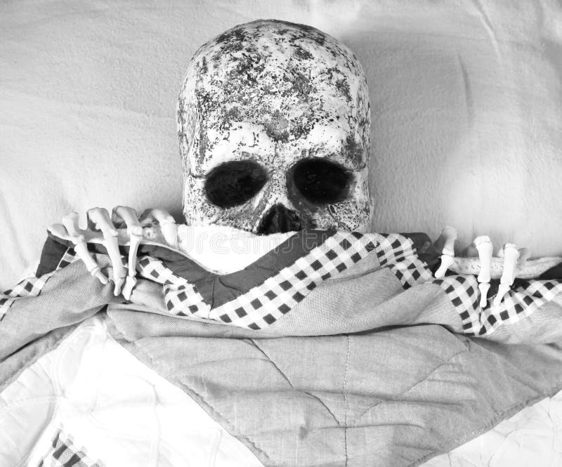 Skeleton peeks out from under the bedcovers. Skeleton peeks out from under the bedcovers