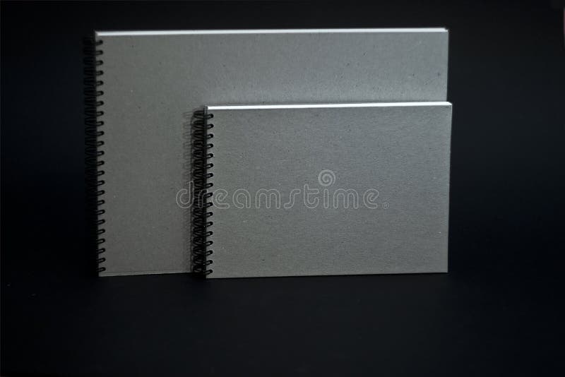 Several Sketchbooks with a Hard Cardboard Cover on a Black Background