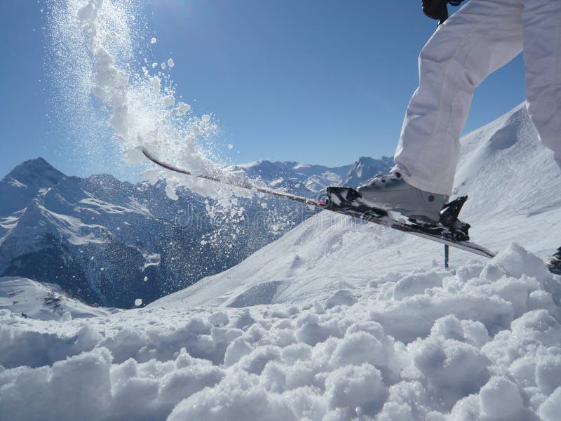Ski fun on a mountain top, throwing snow with a ski. Having fun skiing. Nice to see the sun through the snow
